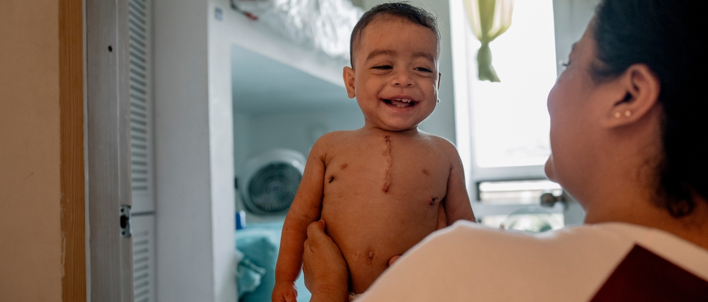 Mom holding baby with scar on his chest.